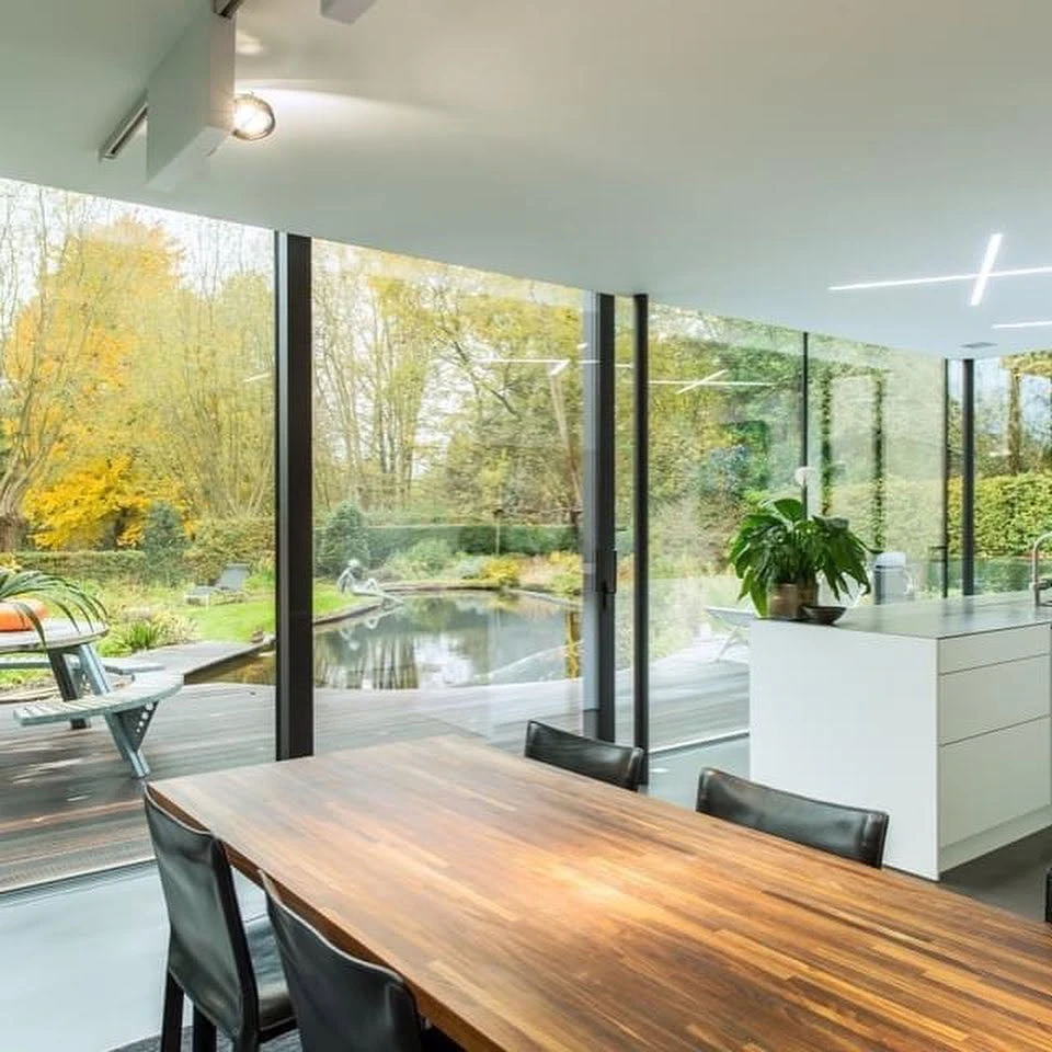 Véranda moderne en aluminium anthracite, structure à toit plat avec couvertine métallique et gouttière intégrée