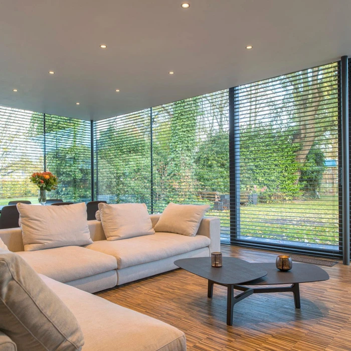 Terrasse extérieure moderne avec pergola bioclimatique à lames orientables en aluminium anthracite, fixée en appui sur façade