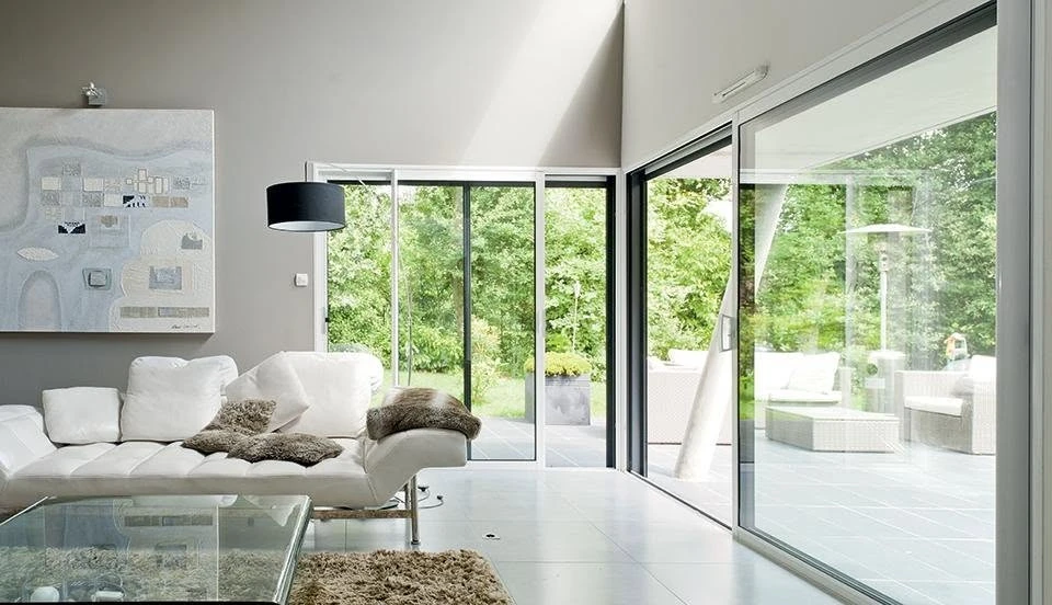 Véranda moderne en aluminium anthracite, structure à toit plat avec couvertine métallique et gouttière intégrée