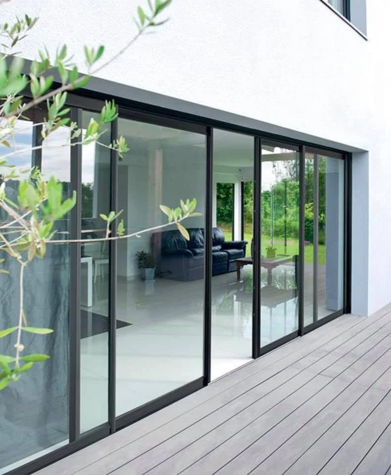 Véranda moderne en aluminium anthracite, structure à toit plat avec couvertine métallique et gouttière intégrée