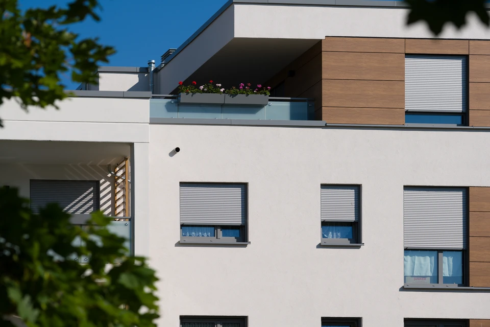 Façade extérieure d'un bâtiment résidentiel moderne avec volets roulants métalliques gris installés sur fenêtres