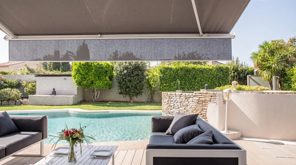 Terrasse moderne avec mobilier d'extérieur haut de gamme sous store banne rayé