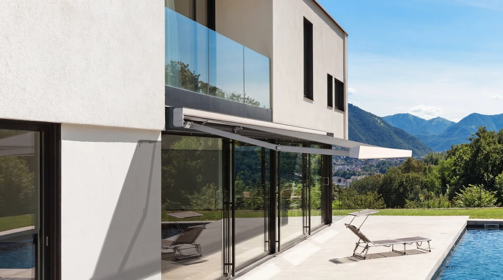 Terrasse extérieure moderne avec pergola bioclimatique à lames orientables en aluminium anthracite, fixée en appui sur façade