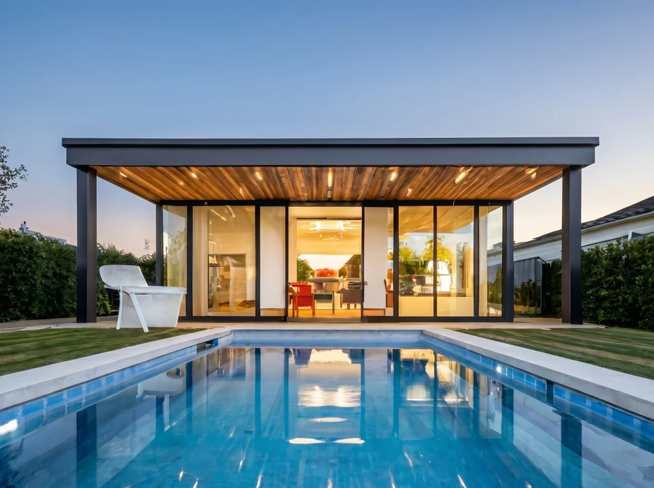 Véranda moderne adossée à une maison, style contemporain, cadre aluminium anthracite, toiture plate avec sous-face en lambris bois naturel, parois vitrées coulissantes, sol en dallage clair sur soubassement brique