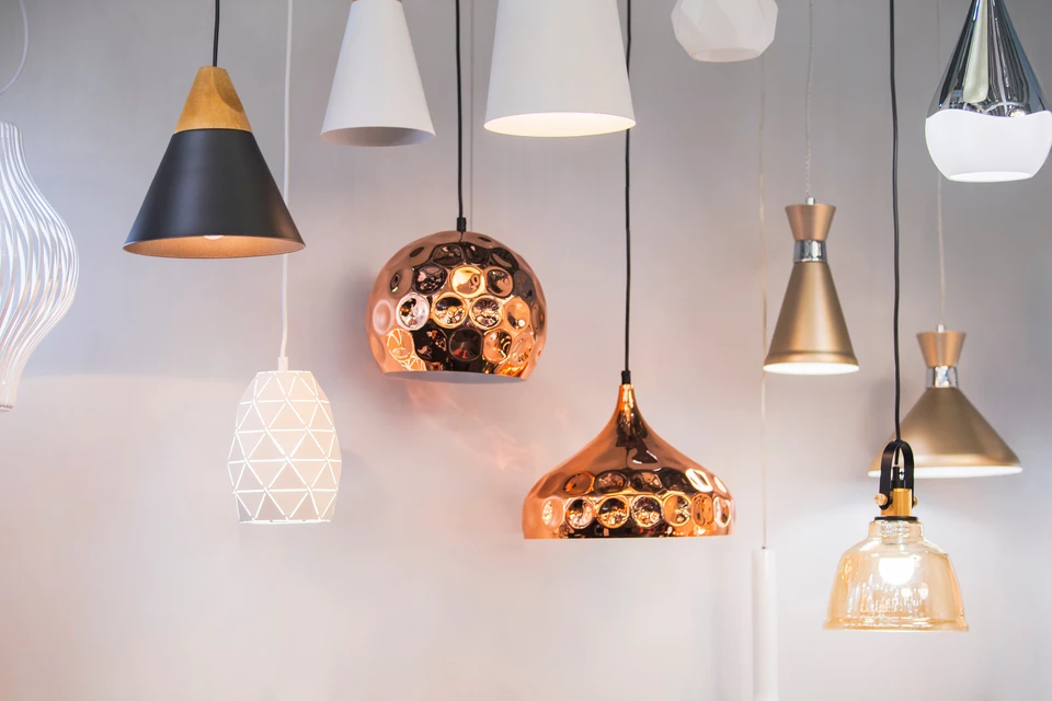 Showroom de menuiserie et fermetures : intérieur moderne et lumineux mettant en scène plusieurs fenêtres aux styles variés (styles modernes, classiques, avec différents matériaux et finitions), des portes d'entrée, des volets, des stores et une pergola partiellement visible. L'espace doit montrer des éléments en exposition sur mesure, bien éclairé, avec des clients ou une conseillère présentant les produits. L'atmosphère doit être professionnelle, accueillante et refléter la qualité artisanale française des produits.