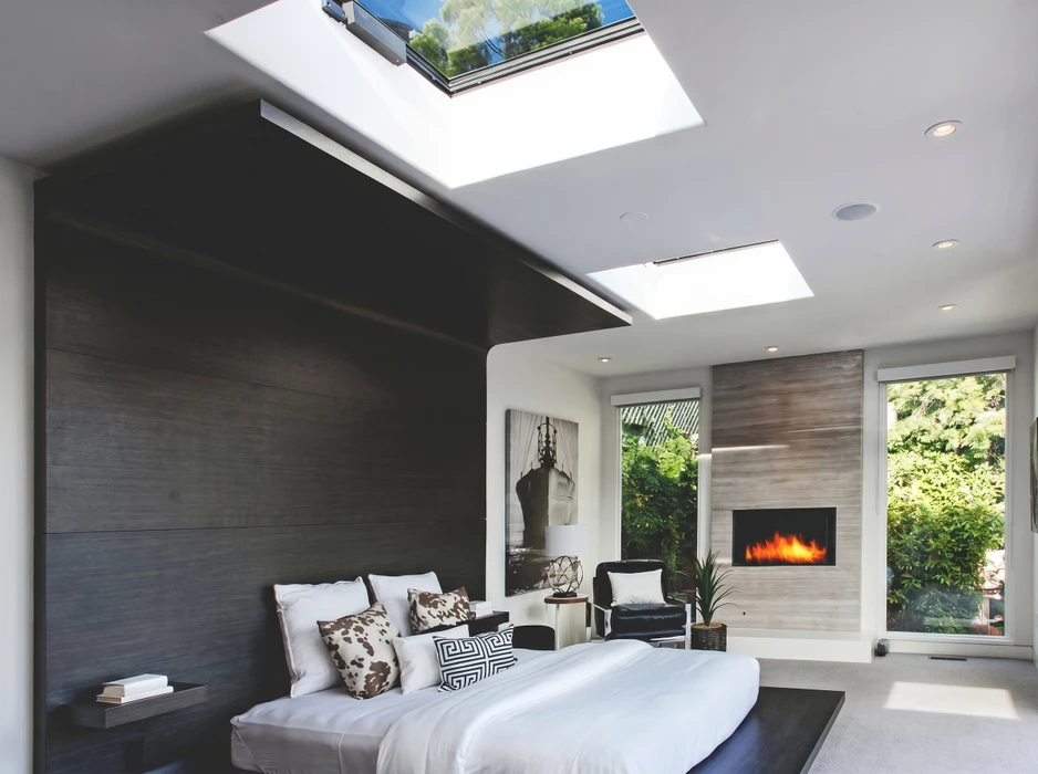 Salon moderne avec canapés gris modulaires disposés face à une grande baie vitrée coulissante donnant sur terrasse et jardin arboré