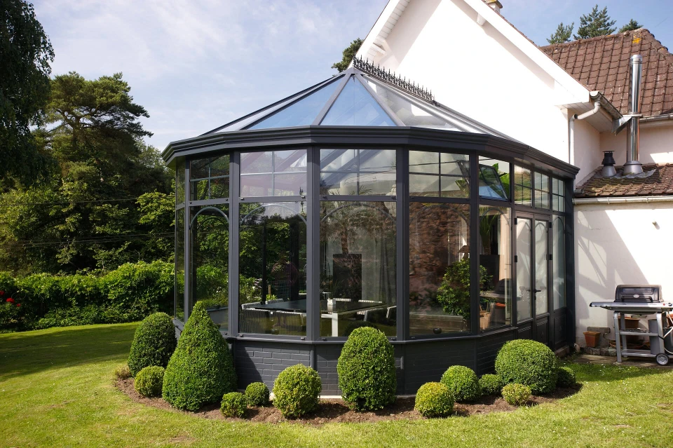 Véranda résidentielle avec structure en bois et verrière, aménagée en salon de jardin