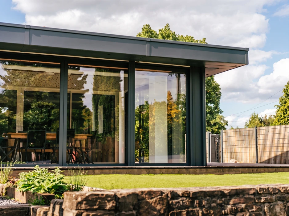 Terrasse extérieure avec plancher en bois composite grisé, balustrade métallique en acier inoxydable avec câbles horizontaux tendus et panneaux de verre dépoli