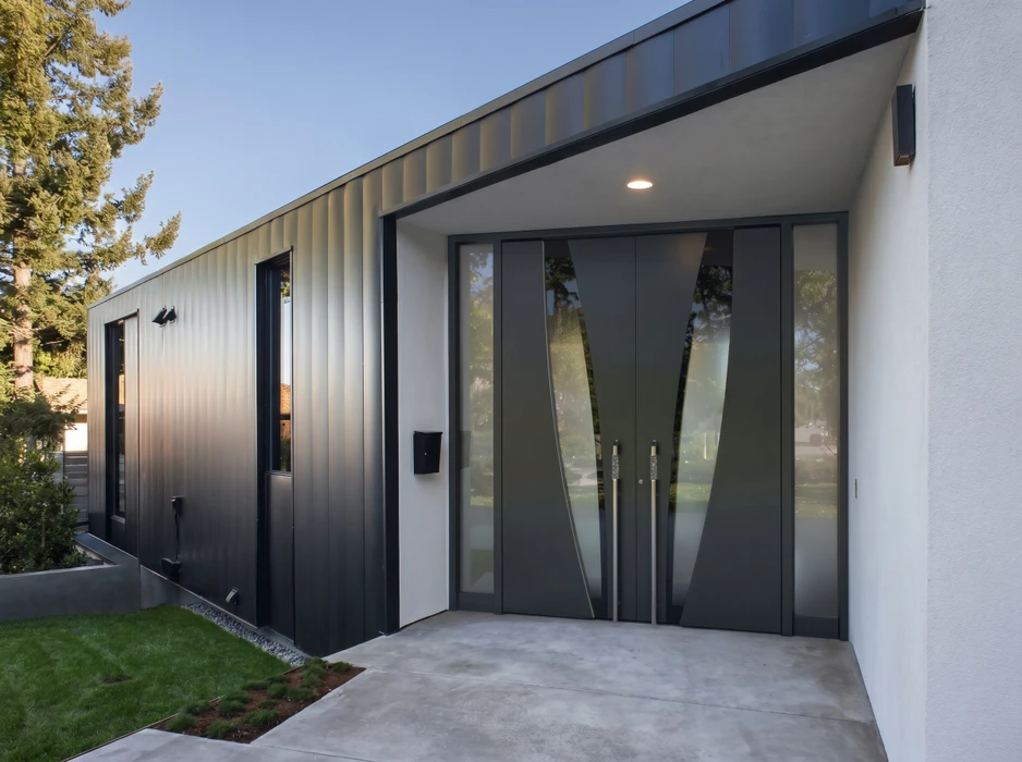 Véranda moderne adossée à une maison, style contemporain, cadre aluminium anthracite, toiture plate avec sous-face en lambris bois naturel, parois vitrées coulissantes, sol en dallage clair sur soubassement brique