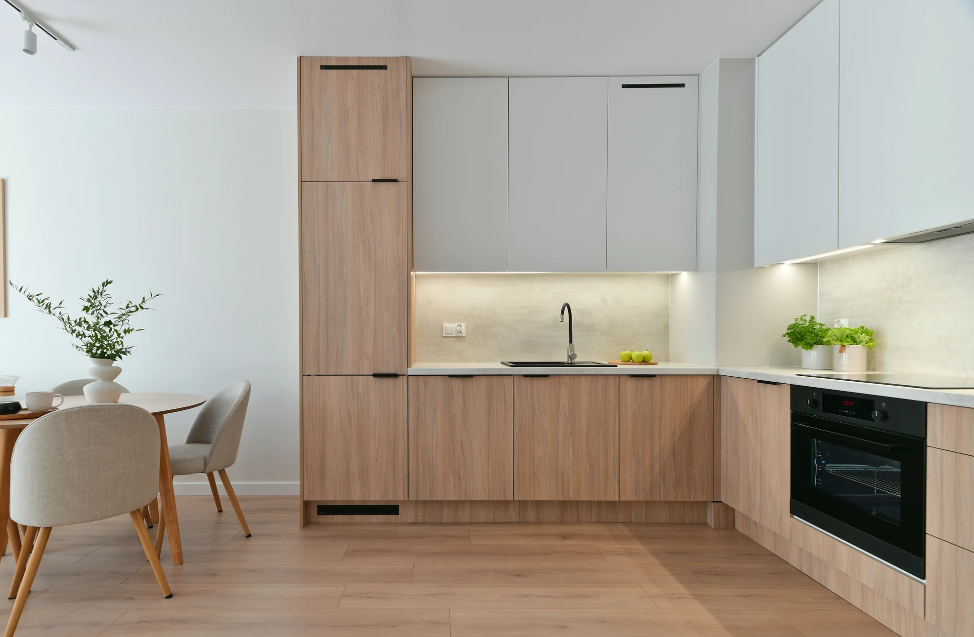 Cuisine moderne avec baie vitrée panoramique ouverte sur un jardin, mettant en avant des fenêtres et portes-fenêtres de qualité avec encadrement en bois ou aluminium. La lumière naturelle abondante illumine un espace culinaire élégant. Le design démontre l'intégration harmonieuse des menuiseries de fermeture (fenêtres, portes vitrées) comme élément central de la pièce, illustrant comment les produits de Génie Créations transforment et valorisent un espace intérieur en le reliant à l'extérieur.